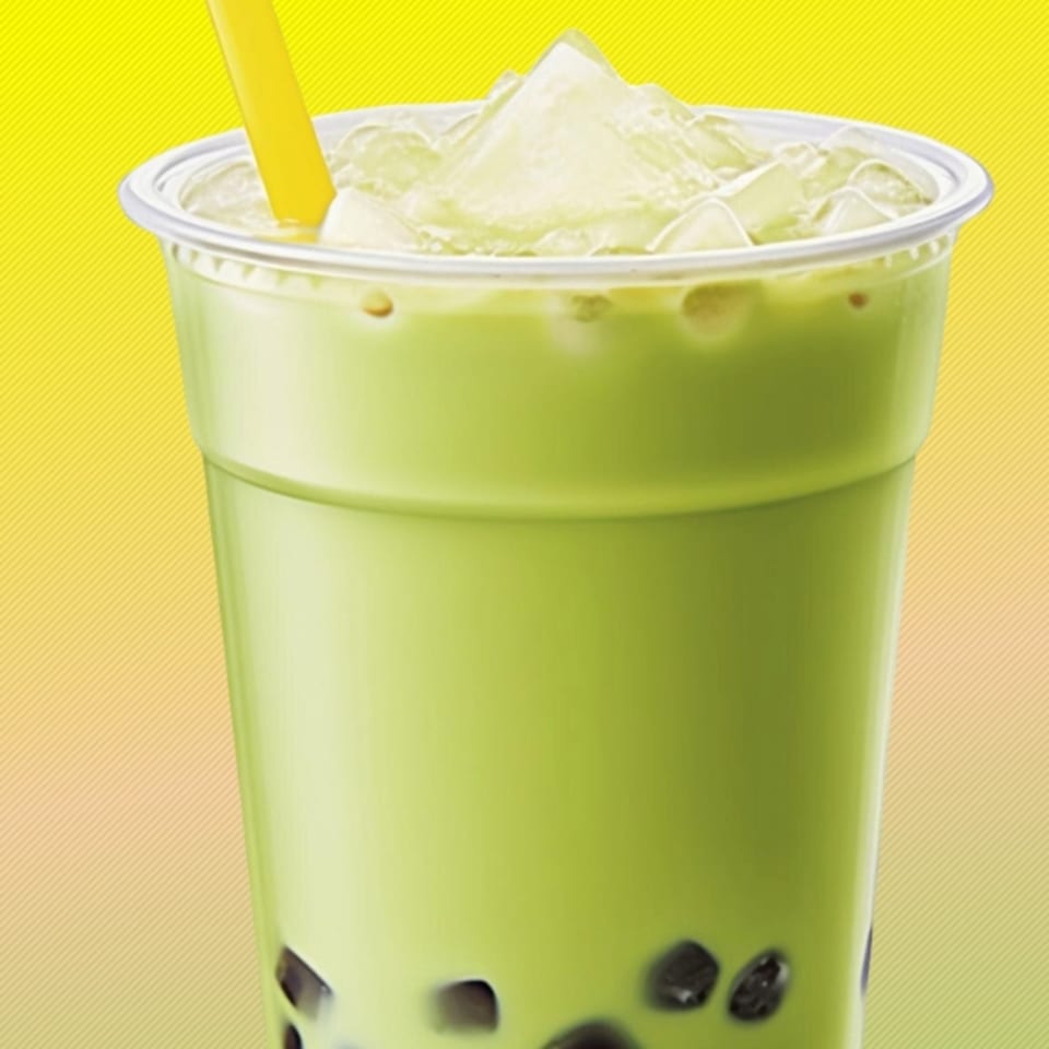 Green boba tea with ice and a yellow straw in a clear plastic cup.