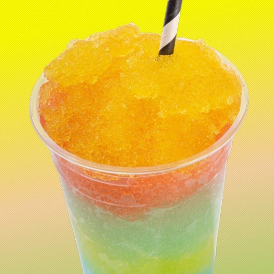 A vibrant, layered shaved ice drink with orange, red, green, and blue colors, topped with a striped straw.